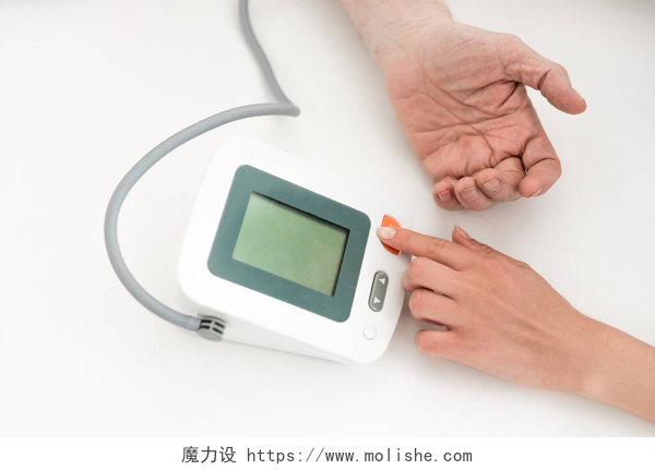 白色背景上使用血压仪测量血压的手在显示复制空间的血压计上的按手按钮裁剪视图